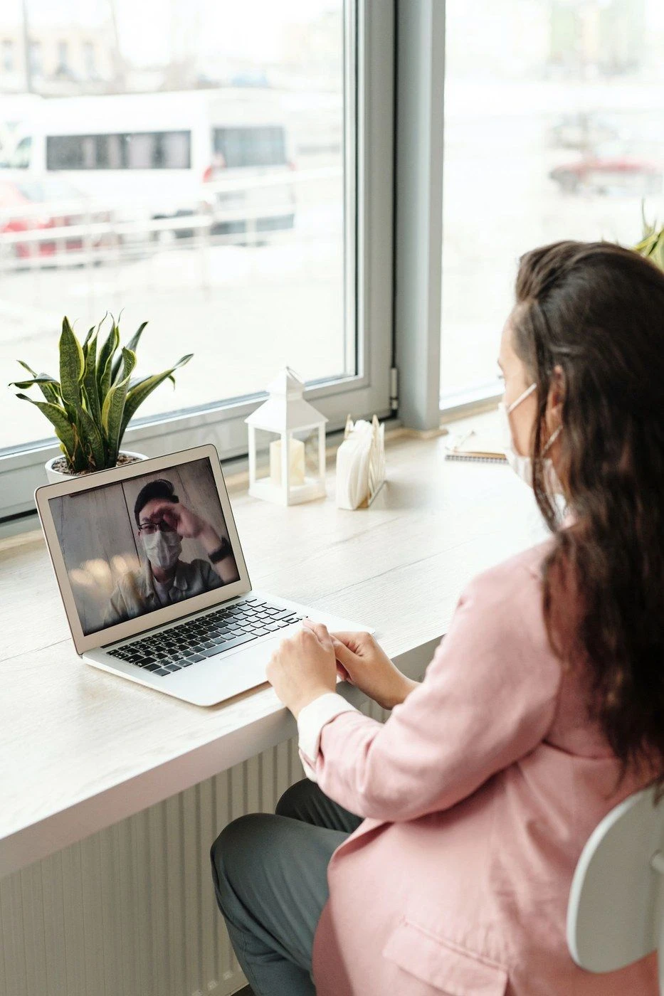 A woman on a video call at a laptop by a window
