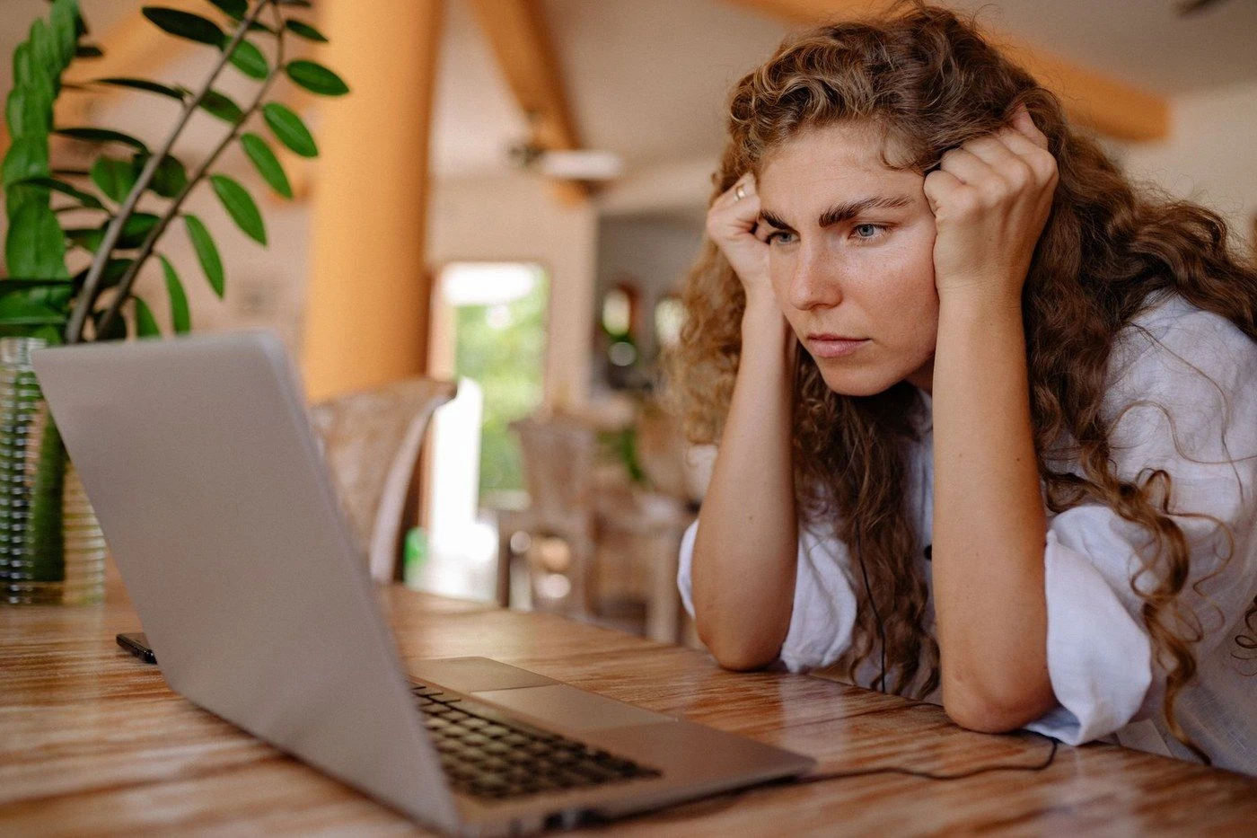 A woman resting her head in her hands in front of a laptop