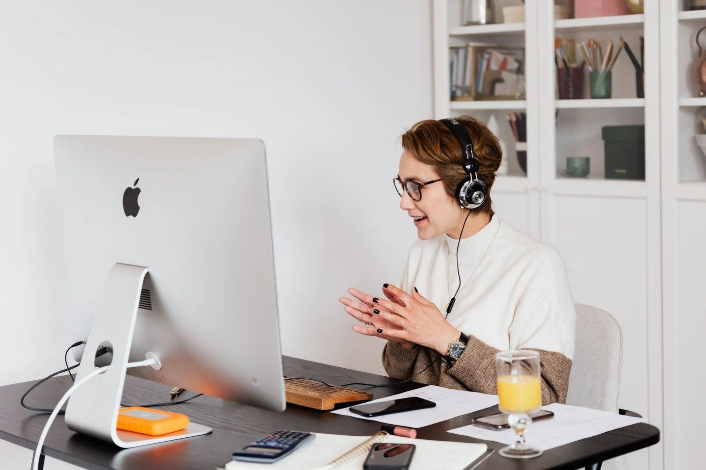 A woman wearing a headset smiling at a computer