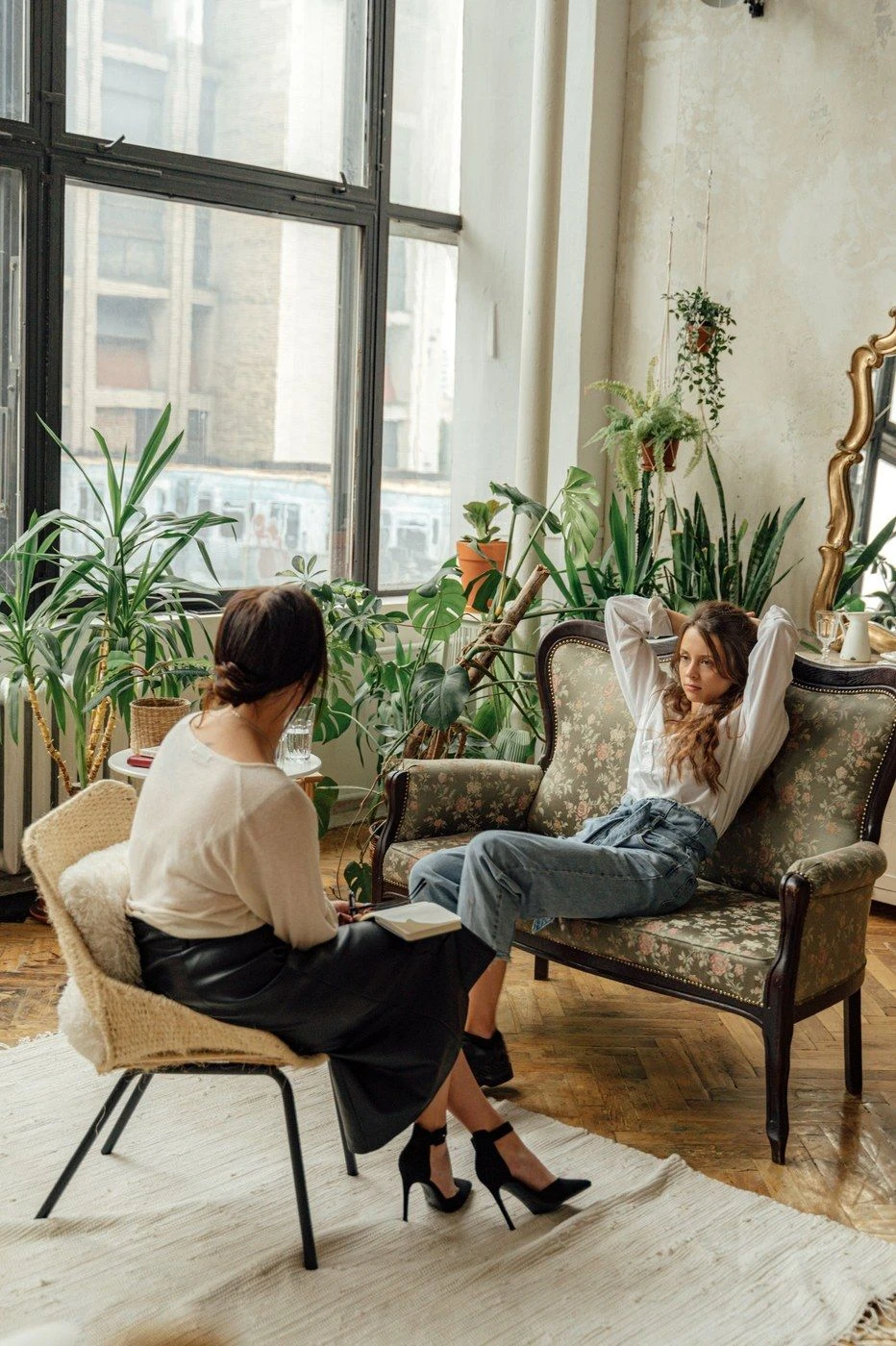 Two women talking in a plant-filled room