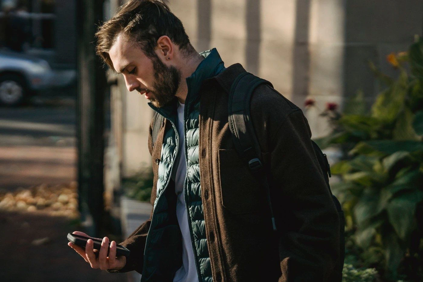A man in a jacket looking at his phone outdoors
