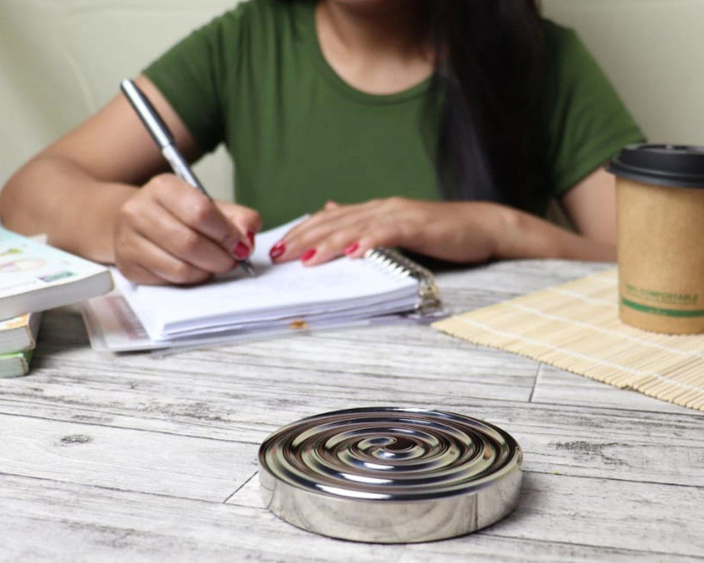 A hand writing in a notebook at a table