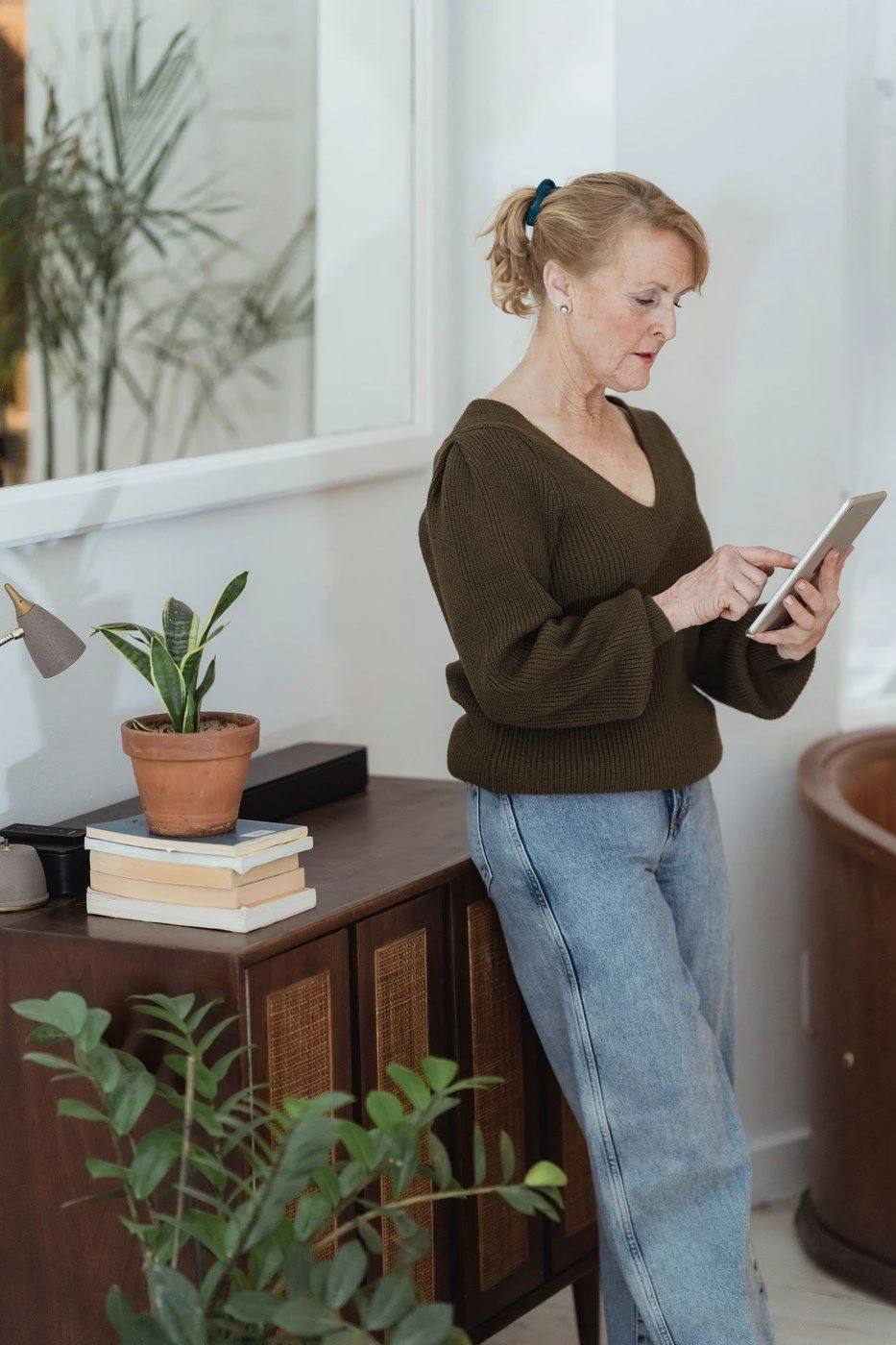 A woman standing in a living room reading a tablet