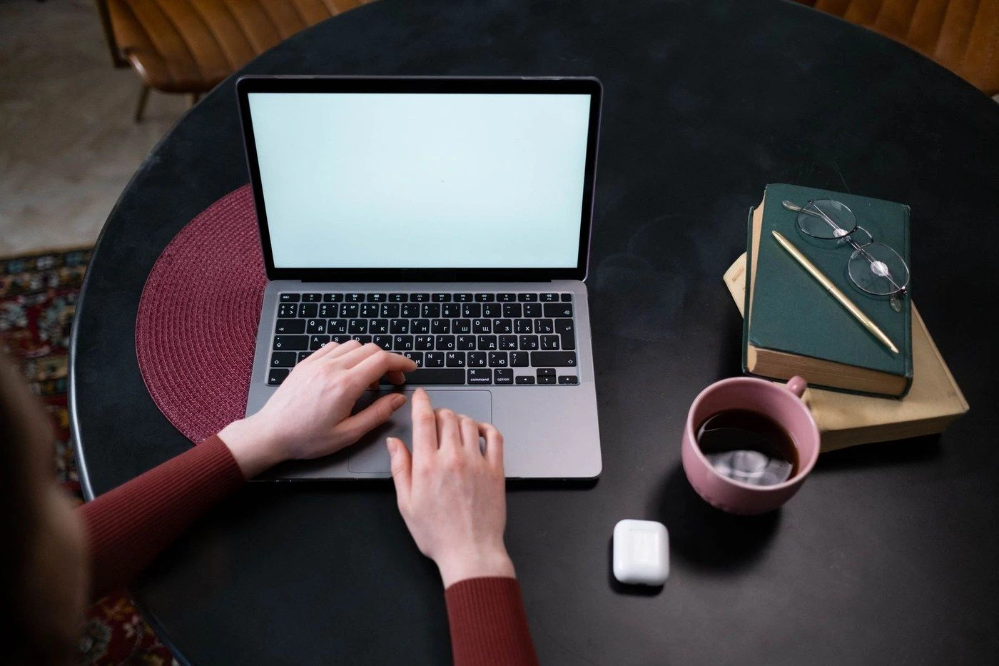 Hands typing on a laptop beside a mug of coffee