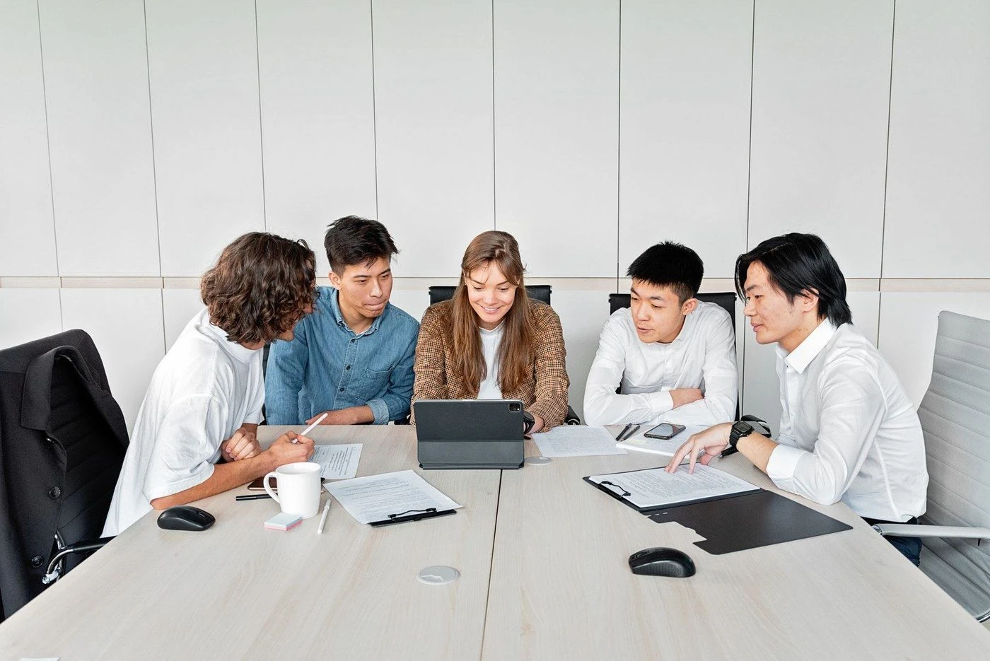 Five colleagues around a table looking at a tablet together