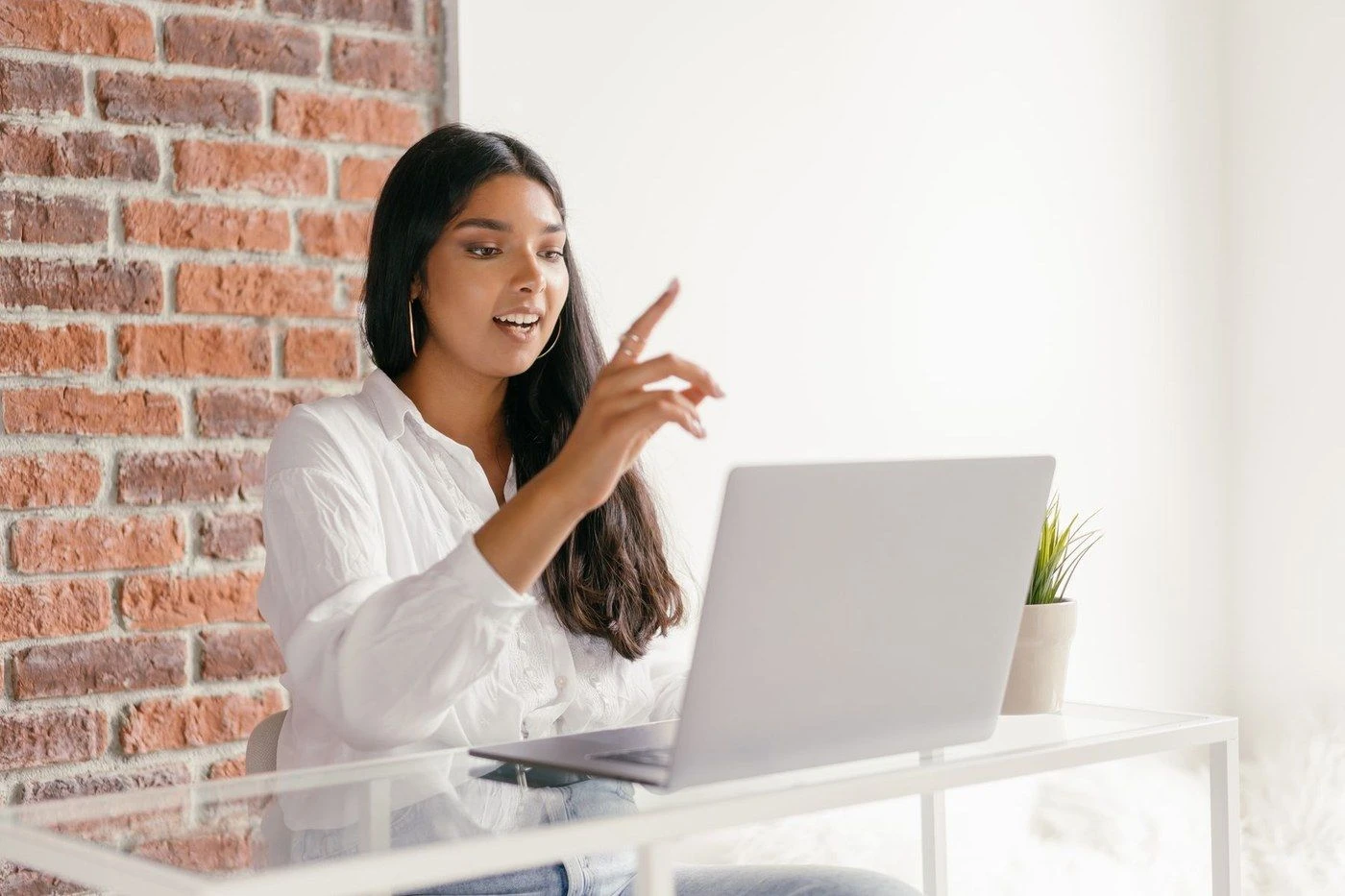 A woman pointing at her laptop screen while talking